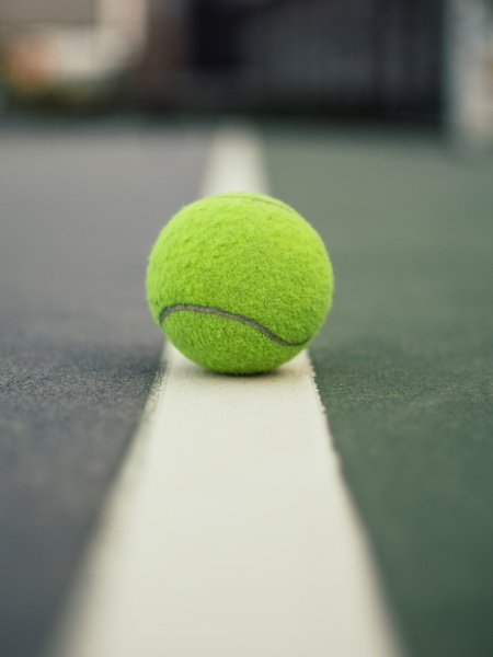 Yellow tennis ball sitting on a court