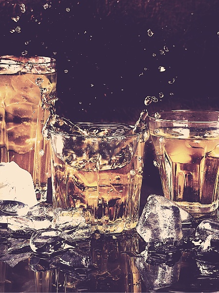 Glasses of scotch on a table and ice cubes scattered around