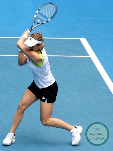 Woman in a white shirt and black shorts and a white visor hitting a tennis ball on a court