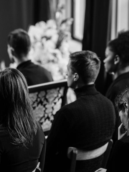 Black and white photo of people sitting in church pews during a funeral service.