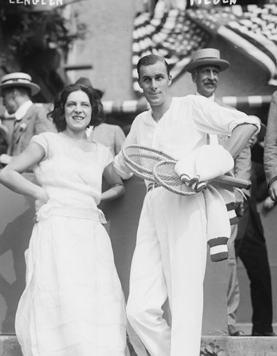 Couple in the 1930s dressed in white with tennis racquets