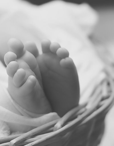 Black and white photo of a baby's feet in a wicker basket.