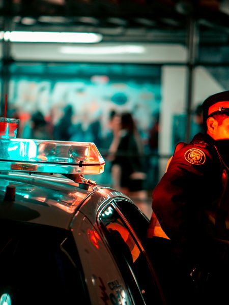 A uniformed police officer next to a patrol car.