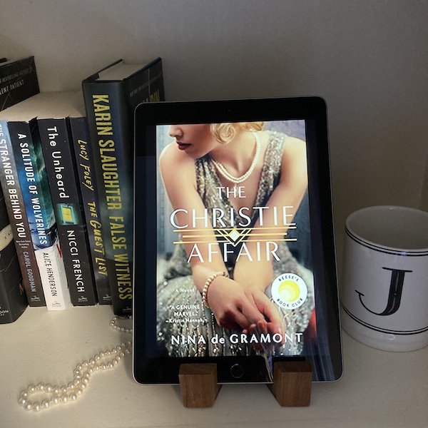 Spoiler Discussion and Plot Summary for the Christie Affair : photo of the book on an iPad, on a shelf with books and a strand of pearls.