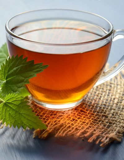 A cup of herbal tea on a burlap coaster with mint leaves