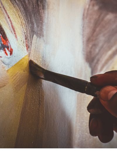 Close up photo of a painter brushing paint on a canvas.