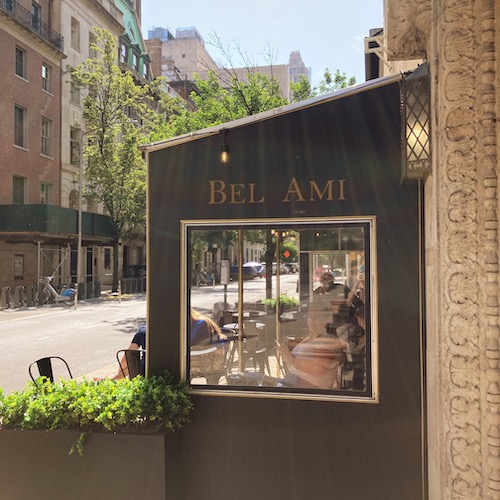 Photo of Bel Ami Cafe awning on a city street. The awning has a square window. Photo by Jen Ryland LLC.