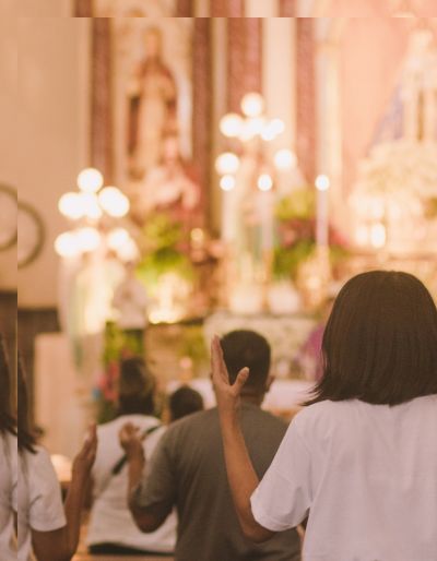 worshippers on pews in a church decorated with candles