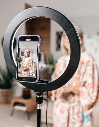 Woman filming a video on her phone with a light ring.