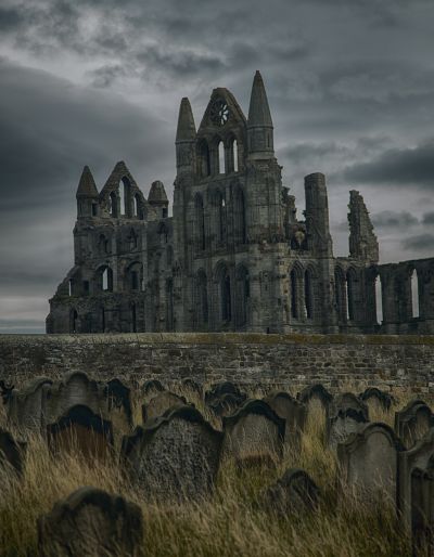 Crumbling ruins of a cathedral under a gray cloudy sky.