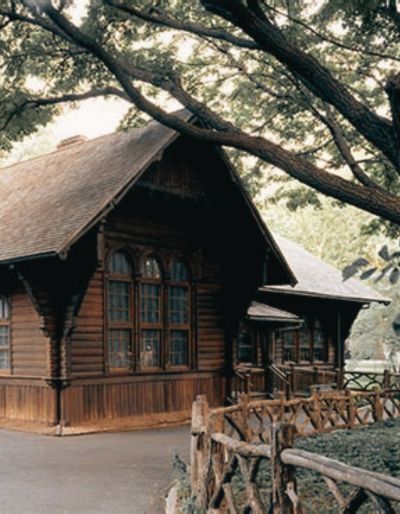 Photo of the Swedish Marionette Theater in Central Park. Photo shows a brown wooden house with arched windows and a rustic fence in the foreground.