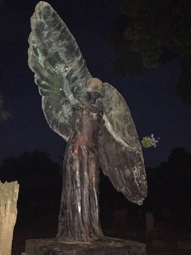 A photo of the Black Angel in the Oakland Cemetery in Iowa City. A sculpture of an angel with one wing pointing up and the other down.