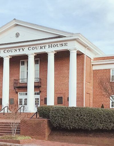 Photo of a red brick building with white pillars and lettering that reads "county courthouse."