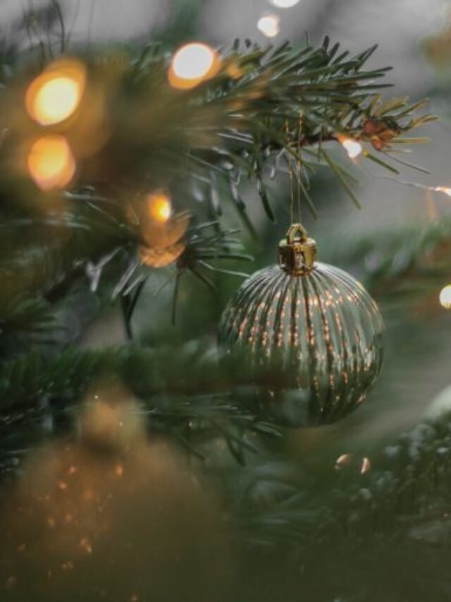 An antique gold and glass ornament hanging on a pine tree