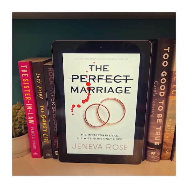 Original photo by Jen Ryland. An ecopy of The Perfect Marriage by Jeneva Rose next to other domestic thrillers on a bookshelf.