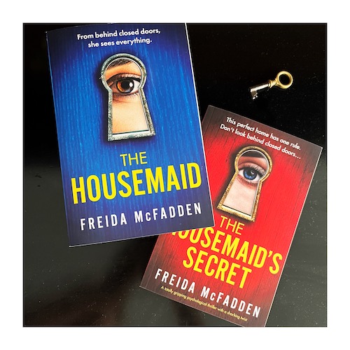 Photo of copies of The Housemaid and The Housemaid's Secret by Freida McFadden on a black background with a key.