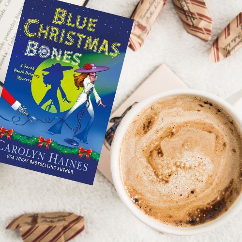 A copy of Blue Christmas bones next to a cup of foamy cocoa