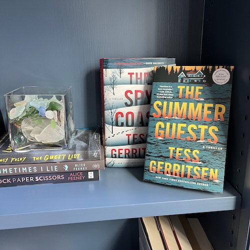 Original photo of The Summer Guests and The Spy Coast by Tess Gerritsen on a blue bookshelf next to a jar of beach glass