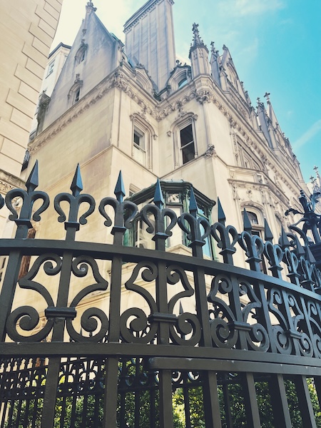 Limestone mansion surrounded by a black iron gate