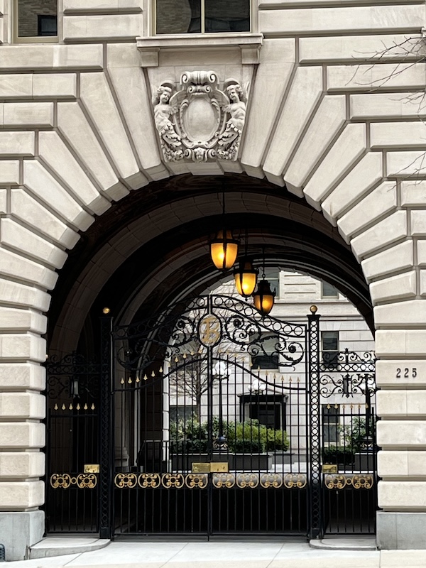 Original photo of the entrance of an Upper West Side building. An arched limestone entrance with wrought iron gates and an internal courtyard