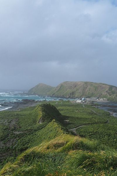 Wikimedia Commons photo of Macquarie Island and the station there. Lush green hills, a mountain and ocean