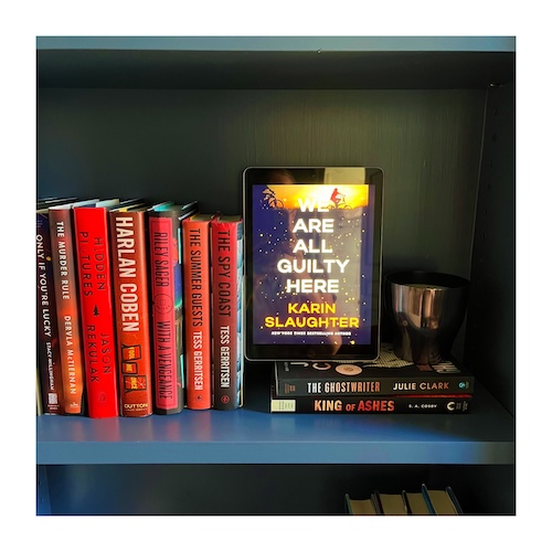 We are All Guilty Here by Karin Slaughter on a blue shelf next to red and yellow books