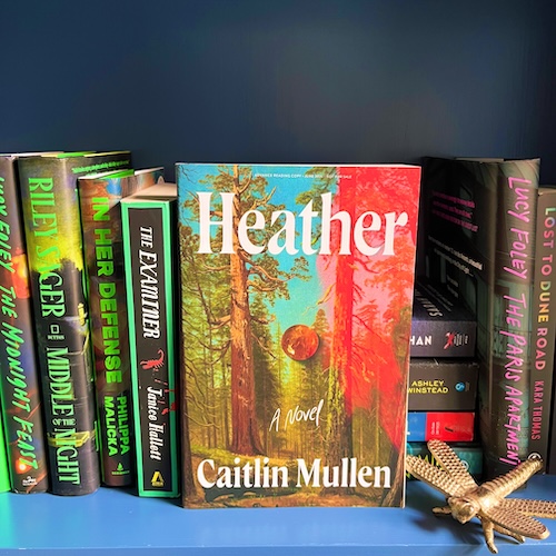 Copy of Heather on a bookshelf next to a gold dragonfly