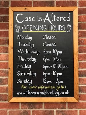 chalkboard sign with hours of the case is altered pub