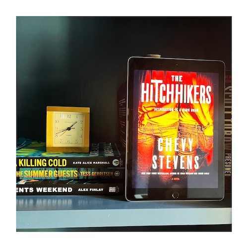 A photo of the cover of The Hitchhikers next to a stack of books and a gold square clock