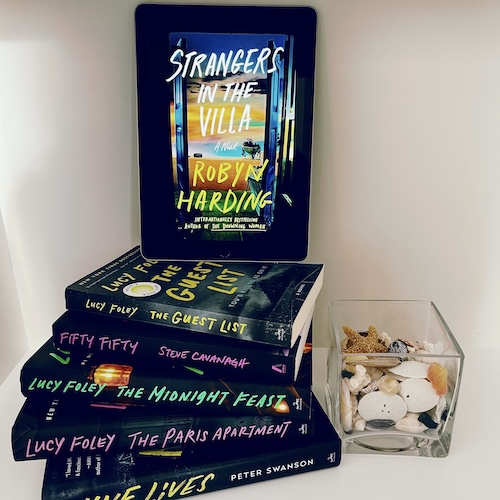 Copy of Strangers in the Villa on a stack of other books with handwritten font titles