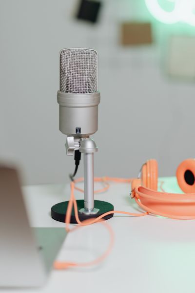 Silver podcasting microphone next to orange headphones