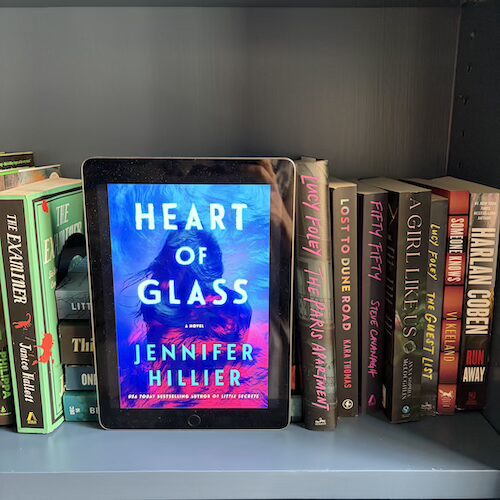 Photo of the cover of Heart of Glass by Jennifer Hillier on a shelf of books