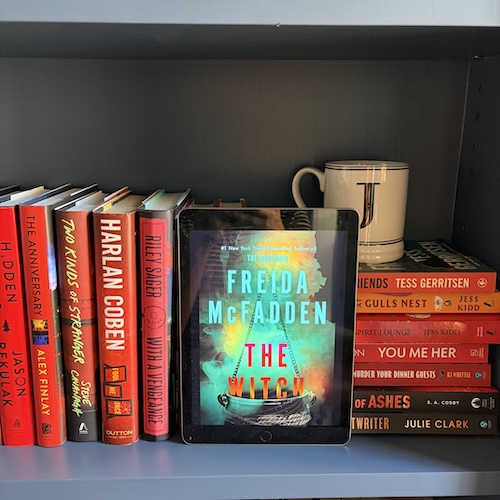 Original photo of The Witch by Freida McFadden on a bookshelf near red books and a J mug